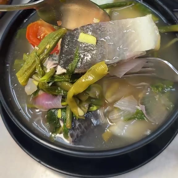 Bowl of sinigang na bangus with a milkfish steak, kangkong leaves, okra, sliced radish, red onion, tomato and a long green chilli in clear sour broth at Pinoy Tambayan