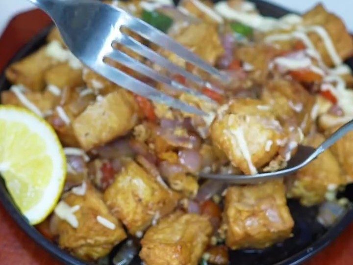 Crispy fried tofu cubes with onion and tomato, drizzled with mayonnaise and served with lemon