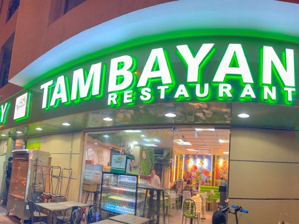 Pinoy Tambayan Restaurant storefront at night with a green and white illuminated sign above the entrance