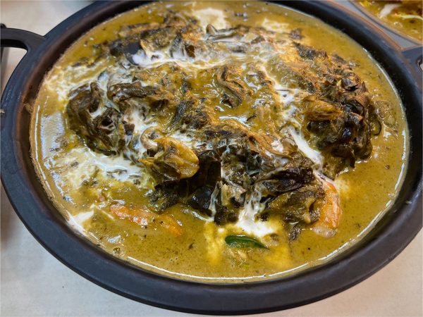 Laing, taro leaves simmered in coconut cream, served with prawns in a black cast iron pan