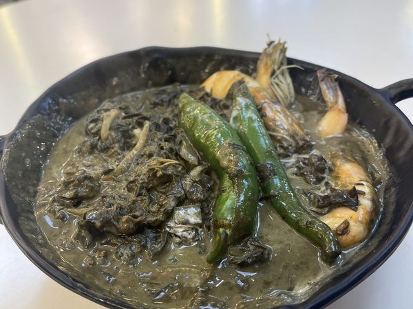 Laing in coconut cream with whole prawns and long green chillies in a black serving pan