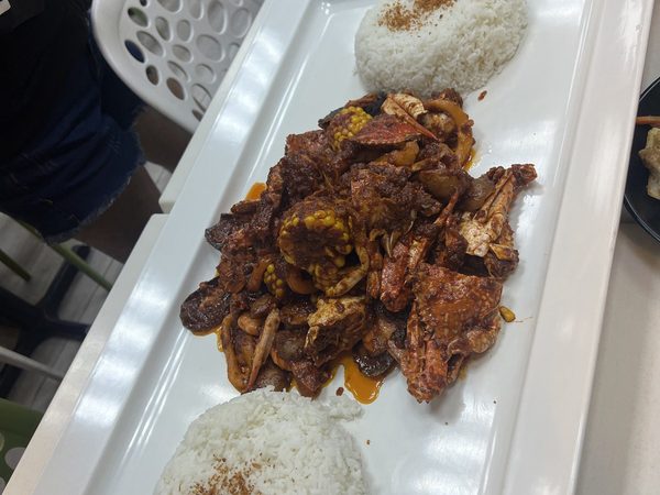 Long white platter of crab, squid and sweetcorn in a dark chilli sauce with two mounds of garlic rice