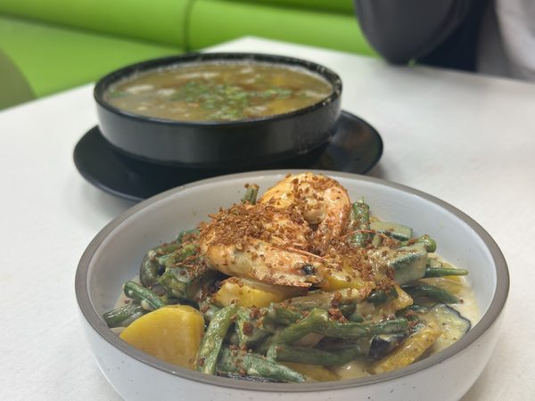 Ginataang gulay of long beans, squash and aubergine in coconut milk topped with a prawn and fried garlic, with a bowl of soup behind
