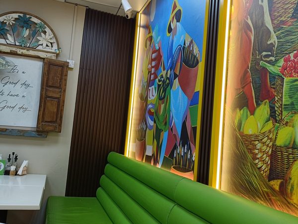 The dining room with green bench seating, backlit Filipino folk art murals and a rustic wall sign reading It's a Good day to have a Good day