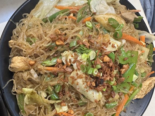 Pancit bihon guisado with rice vermicelli, cabbage, carrots, snow peas, chicken and pork, topped with fried garlic and spring onion