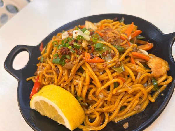 Pancit canton noodles with pork, carrots, cabbage and spring onion, topped with fried garlic and a lemon wedge