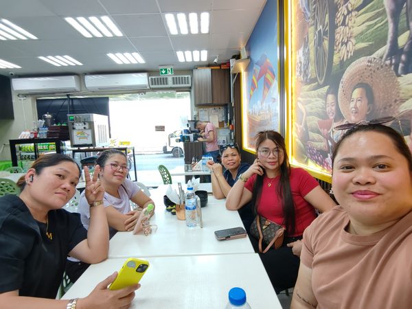 Five women posing for a selfie around a long table in the restaurant's dining room, with the Filipino murals and service counter behind them