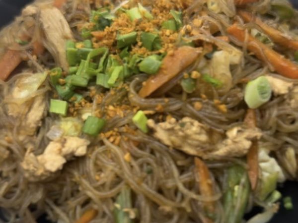Pancit bihon, thin rice noodles tossed with chicken, carrots, cabbage and egg, topped with spring onion and fried garlic
