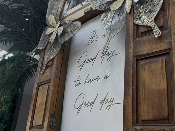 Rustic wooden window-frame wall decor with metal butterflies and flowers around a script sign reading "It's a good day to have a good day".