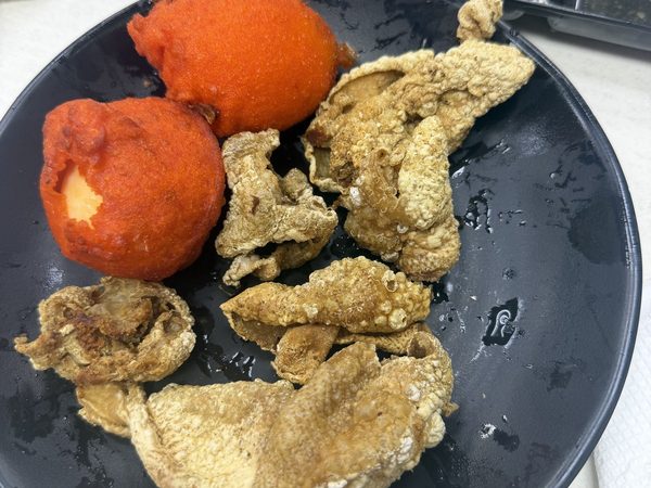 Plate of crispy chicharon bulaklak with two orange-battered kwek kwek quail eggs and a tray of three dipping sauces.
