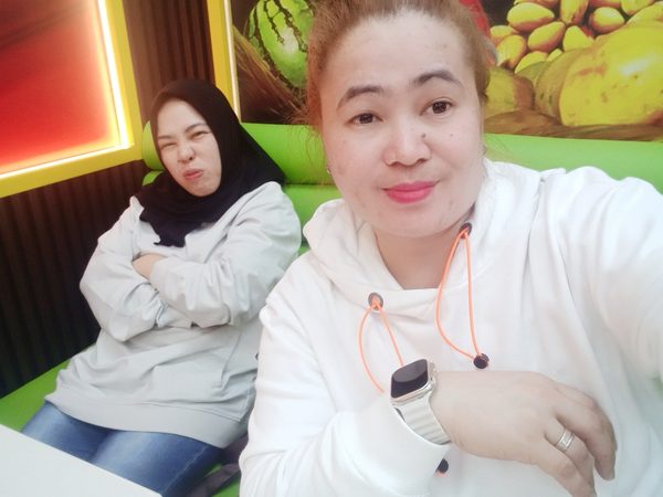 Selfie of two women sitting in a green booth in front of the restaurant's painted fruit harvest mural.