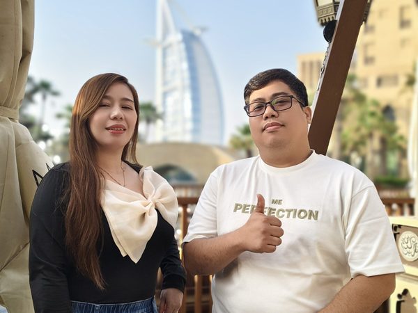 Two adults posing outdoors at Madinat Jumeirah with the Burj Al Arab in the background; not taken at the restaurant.