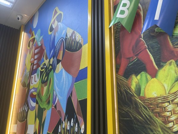 The restaurant's wall murals, a cubist Filipino market painting and a painted fruit harvest scene, above green booth seating with birthday bunting.