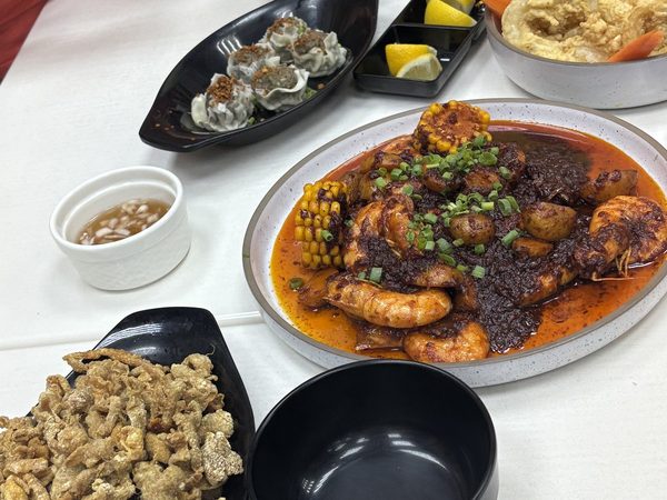 Shared table spread of chilli garlic prawns with corn, crispy pork chicharon, steamed siomai dumplings and battered calamari rings.